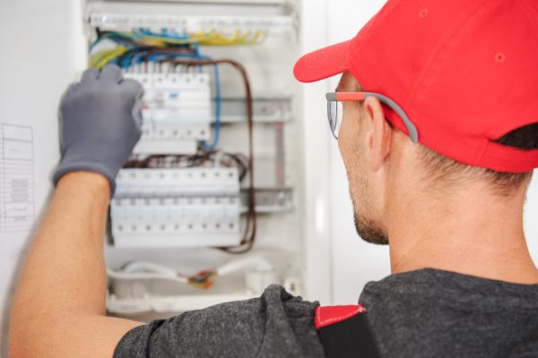 A skilled electrician inspects and repairs a residential circuit box, ensuring proper electrical connections and safety measures in a home environment.